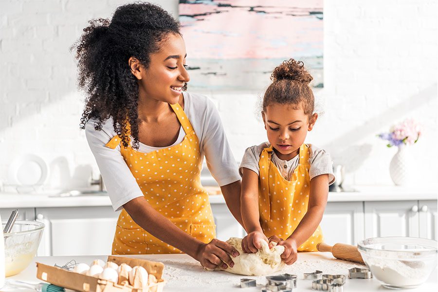 Employee Benefits - Portrait of Mother and Daughter Kneading Dough in Their Modern and Updated Kitchen on a Sunny Day