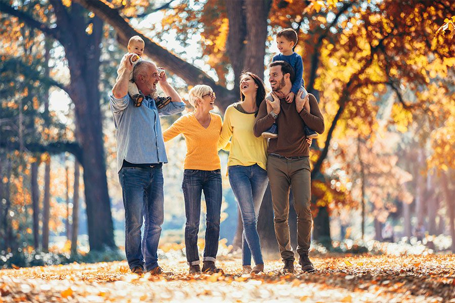 Personal Insurance - Multi-Generational Family Walking Side by Side Together Having Fun in the Park with Lots of Trees and Leaves Changing Color in the Fall