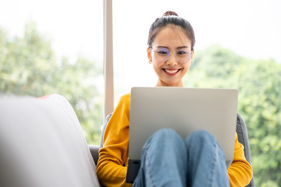 Video Library - Woman Having a Conversation and Chatting While Using Her Laptop at Home and Sitting on the Sofa