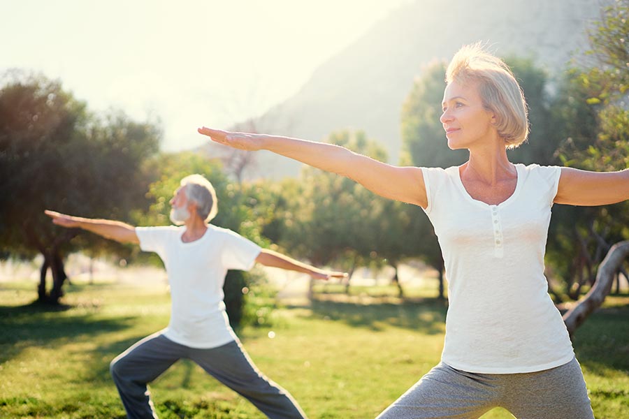 Health Insurance - Senior Couple Exercising and Doing Yoga at a Local Park Outdoors on a Summer Day at Dusk